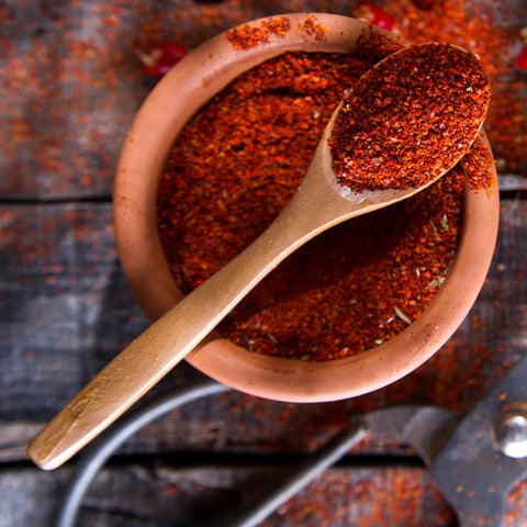 Smoked chilli Powder in a clay bowl with a wooden spoon