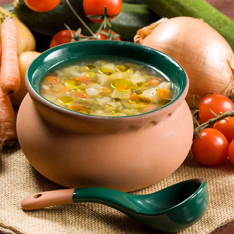 Bowl of vegetable soup surrounded by vegetables
